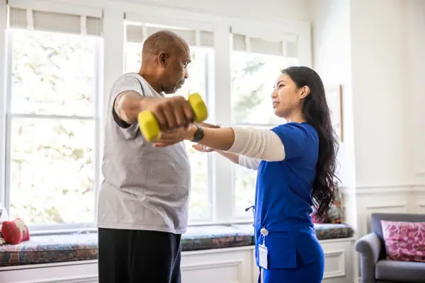 Rehabilitation clinician guiding an older adult through a light strength exercise session