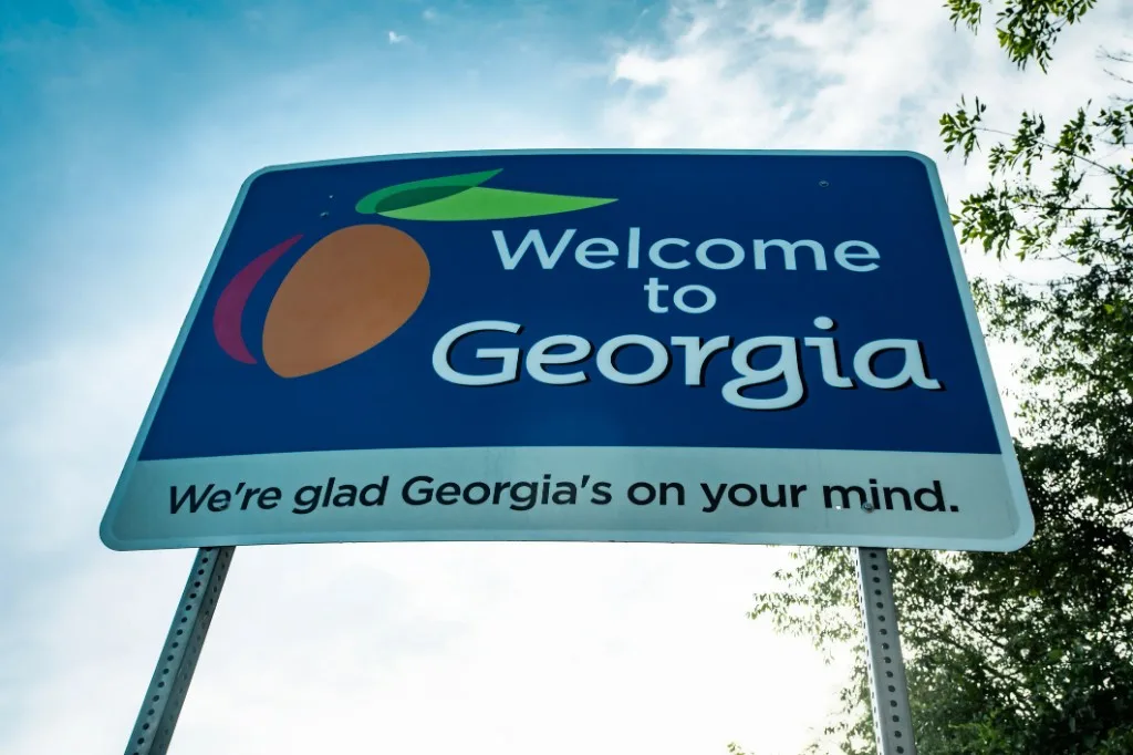 Welcome to Georgia roadside sign with a peach logo against a bright sky